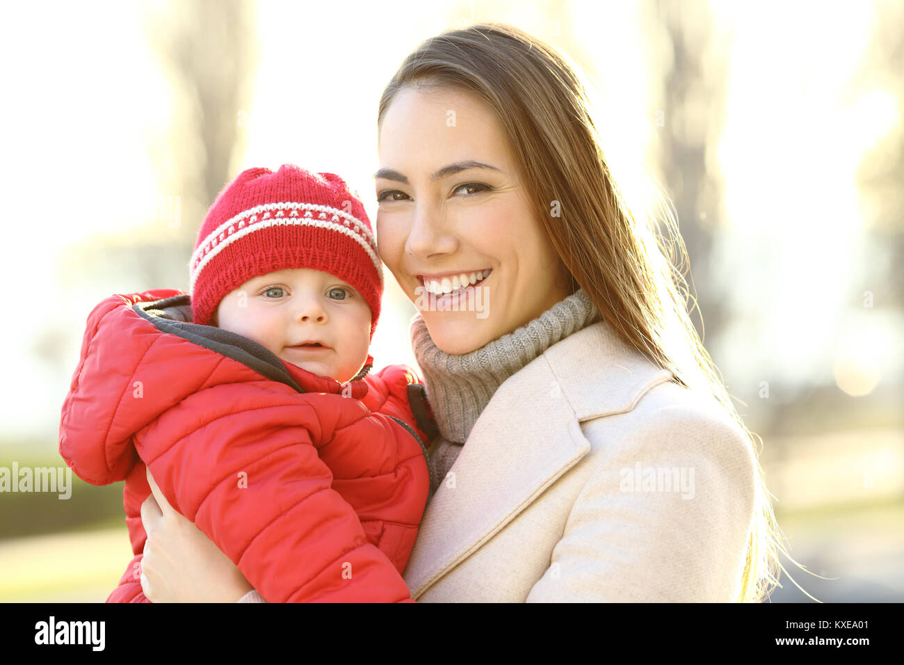 Portrait of a happy mother posing with her baby son looking at you outdoors in winter Stock Photo