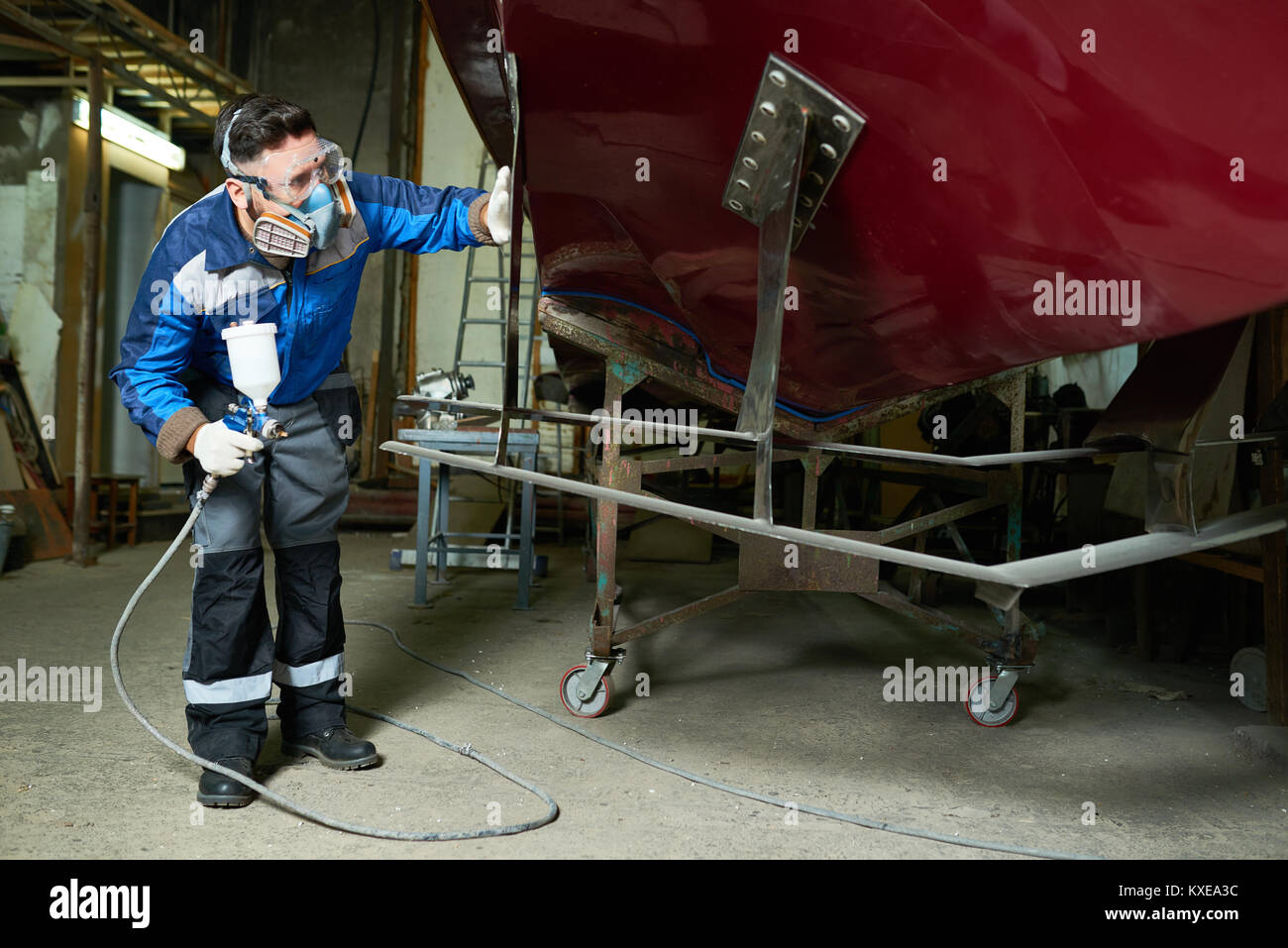 Full length portrait of worker wearing protective mask checking coating