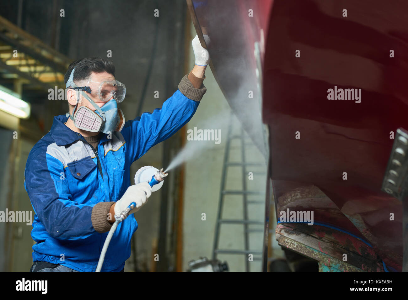 Side view portrait of worker wearing protective mask spray painting