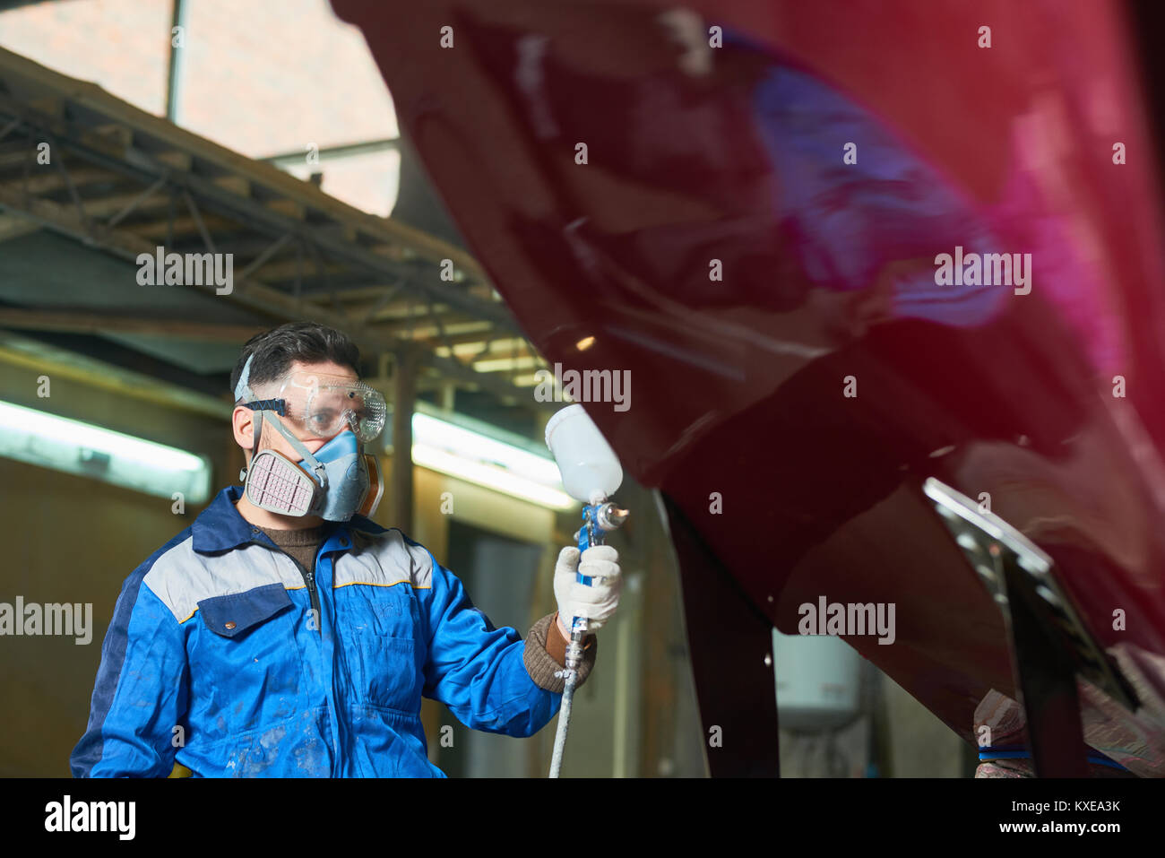 Portrait of man wearing protective mask painting boat using paint