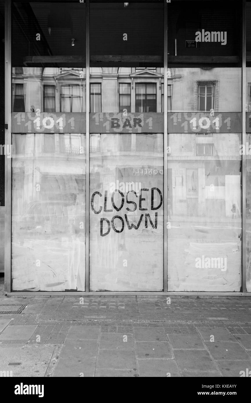 The words "Closed Down' etched into the whitewash inside a retail space