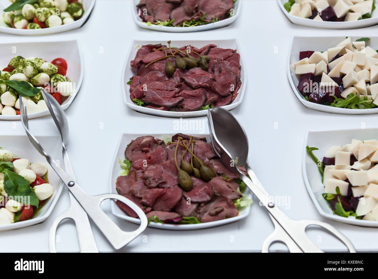 Plate of cold cuts with capers. Sliced meats in a white plate with capers on a white table. Meat with capers Stock Photo