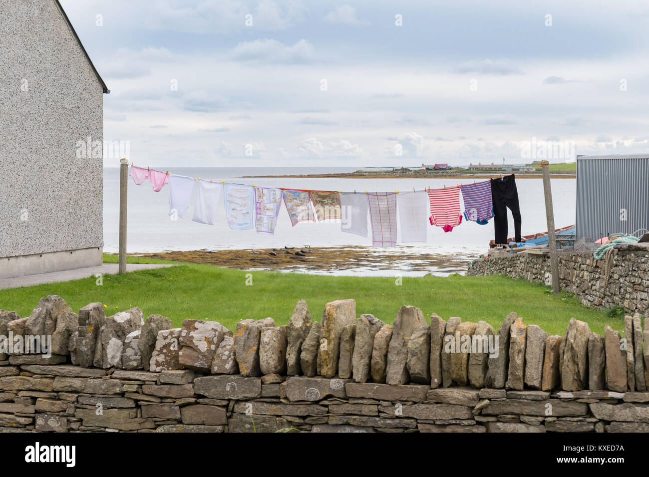 line of washing blowing in the wind next to the sea on the Orkney Island of Westray, Scotland, UK Stock Photo