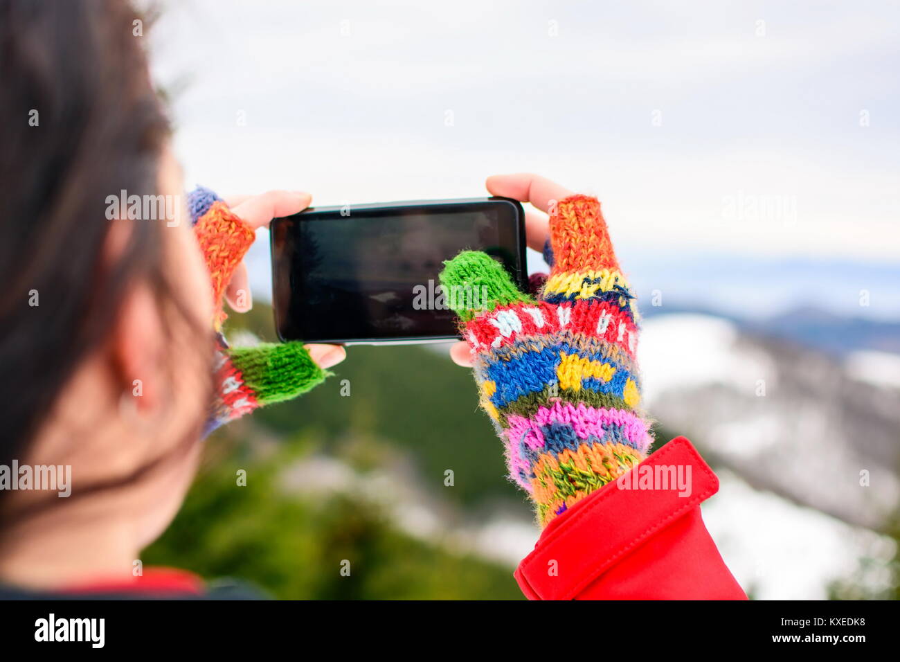 Girl taking picture of beautiful winter scenery with a smart phone Stock Photo
