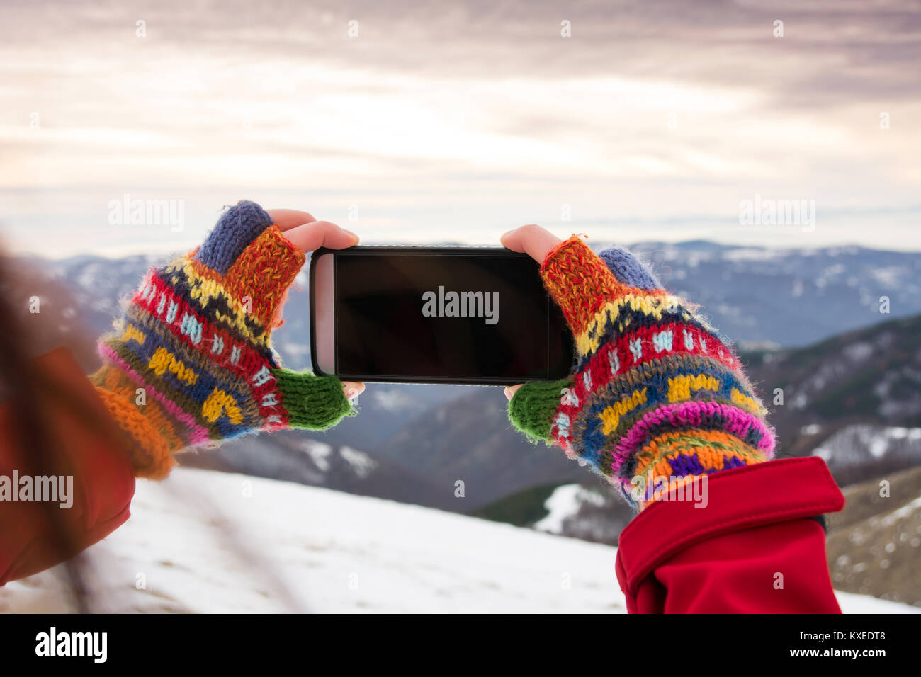 Girl taking picture of beautiful winter scenery with a smart phone Stock Photo