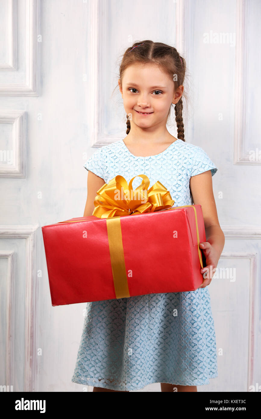 Beautiful cute kid girl holding big present box with red ribbon bow and ...