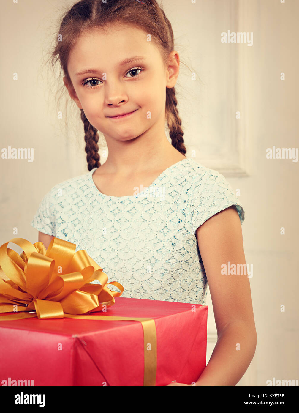 Beautiful cute kid girl holding big present box with red ribbon bow and ...