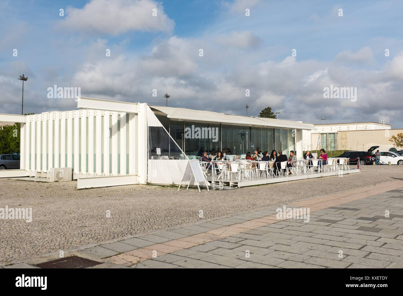 People sitting outside A Margem restaurant and cocktail bar in Belem enjoying late autumn sunshine whilst having a drink Stock Photo