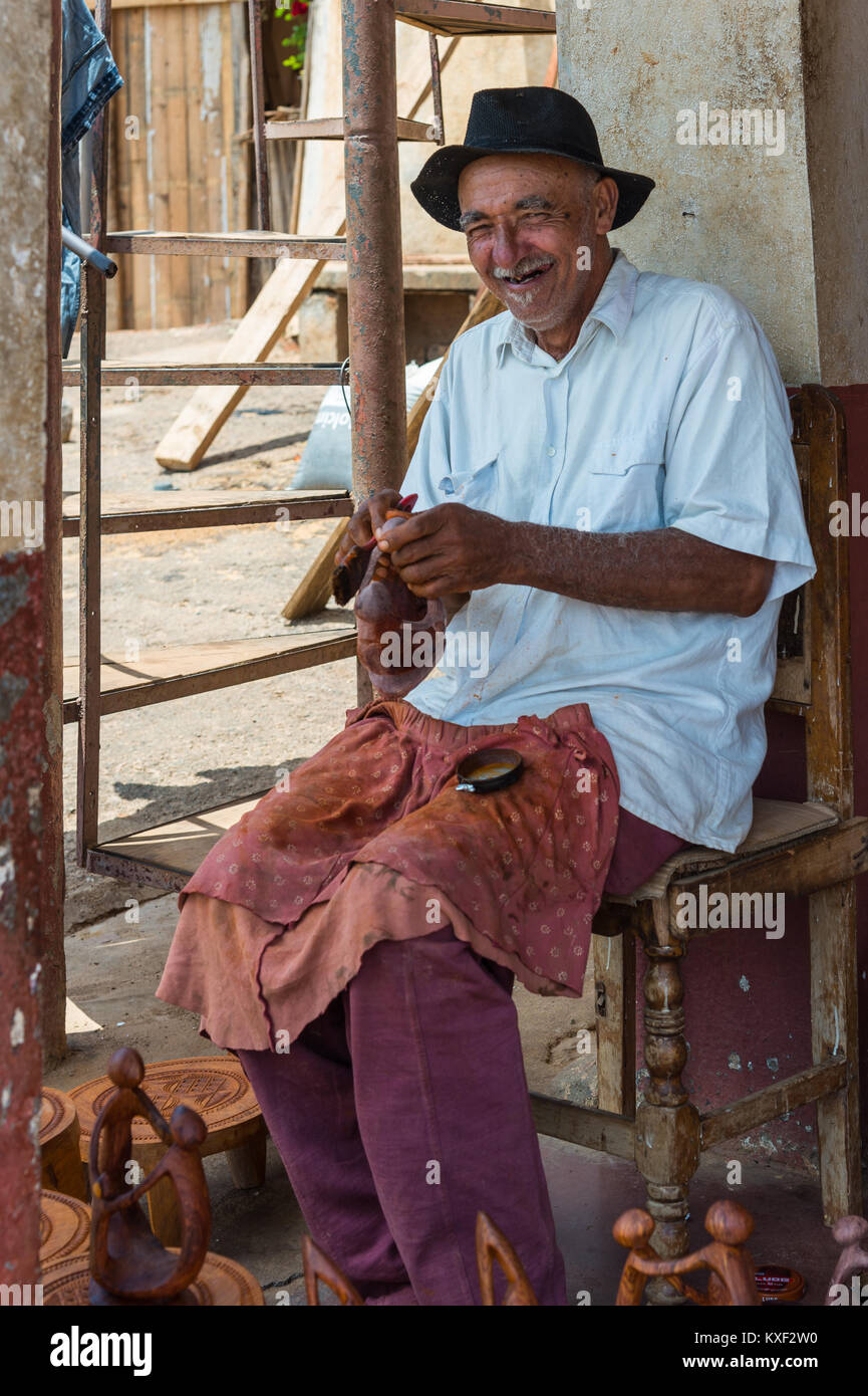 An old man working on wood craft in front of his store. Madagascar, Africa. Stock Photo
