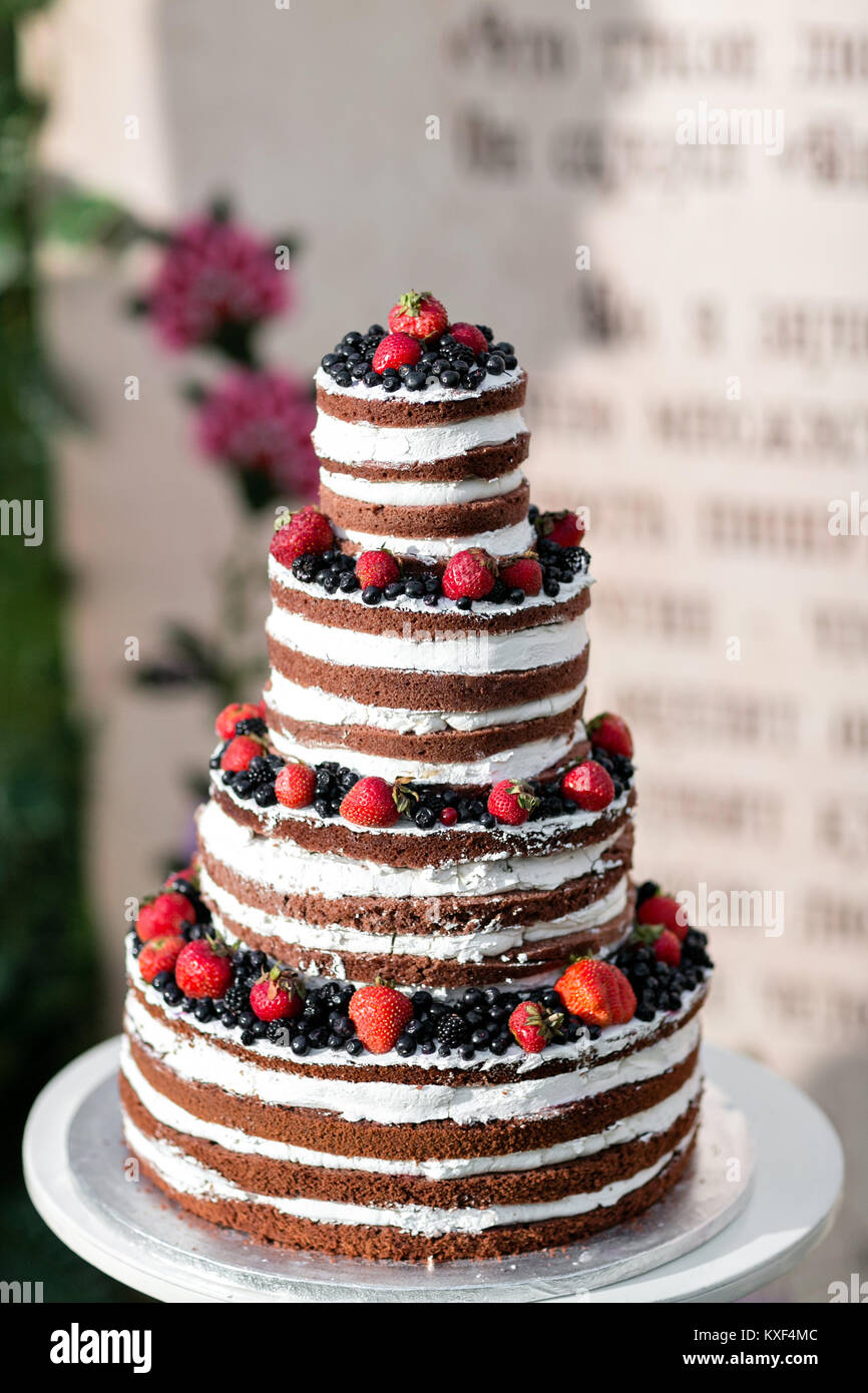 Round multi tiered wedding cake with sponge, cream, jam and berries on ...