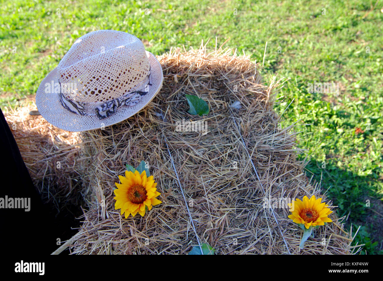 countryside image with peasant straw hat and sunflowers resting on hay Stock Photo
