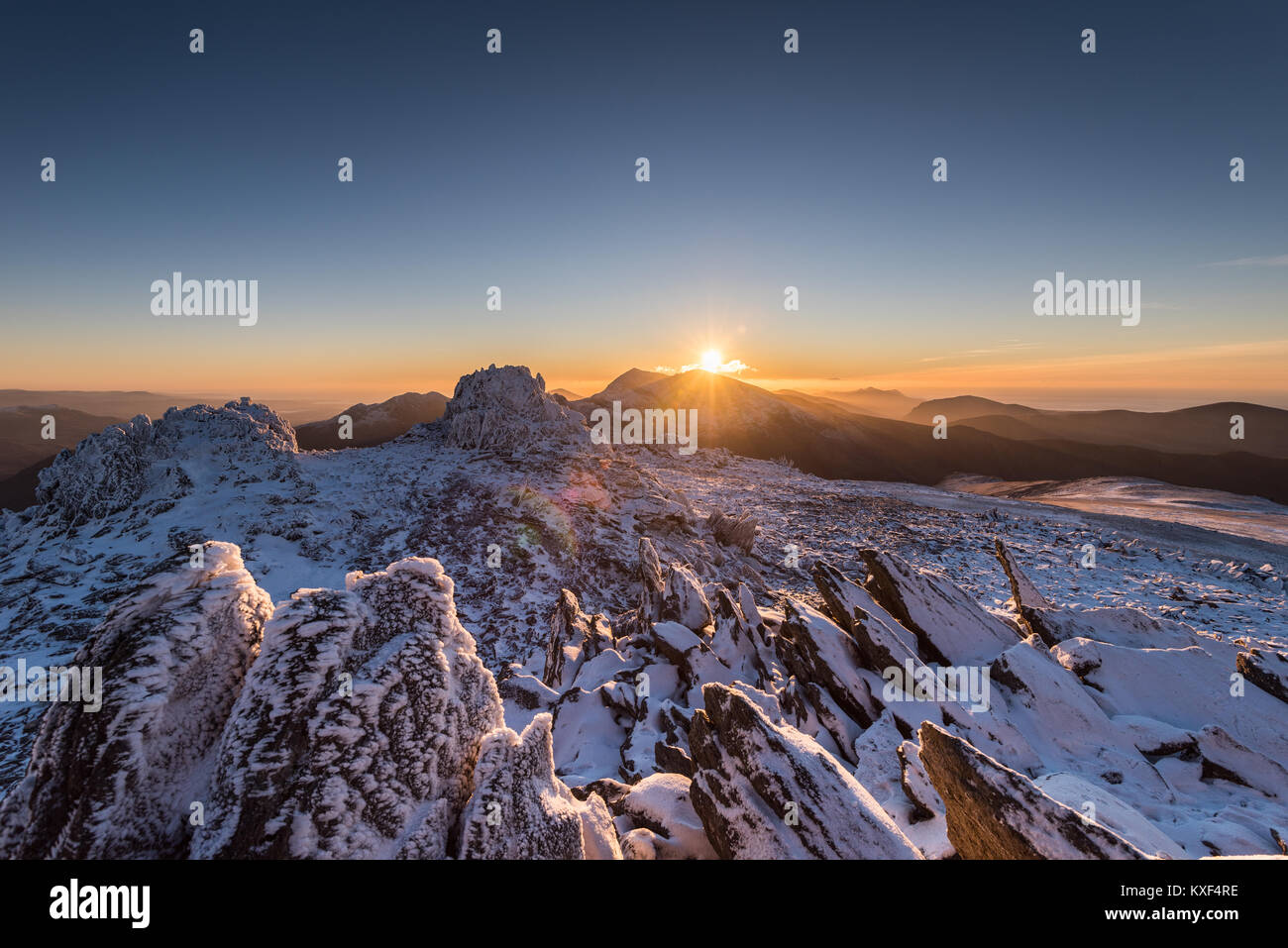 figure on snowy mountain in Wales with sunset Stock Photo