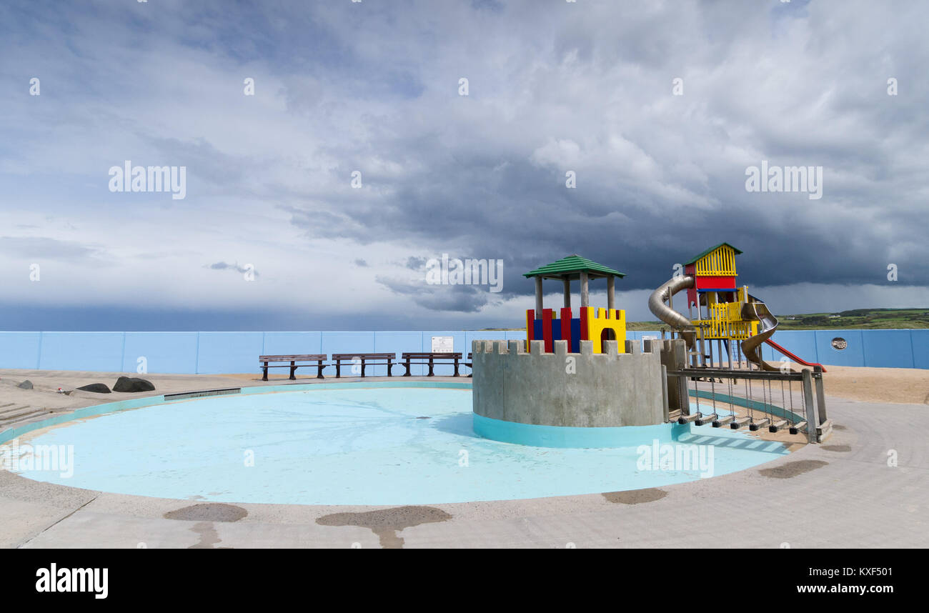 A chidrens' playground and padding pool with a stormy sky in the background. Stock Photo