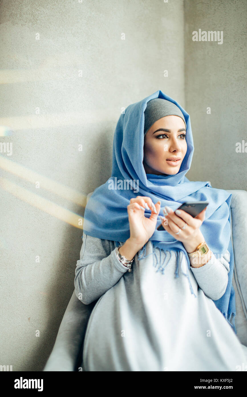 Young woman sitting and holding mobile phone Stock Photo - Alamy