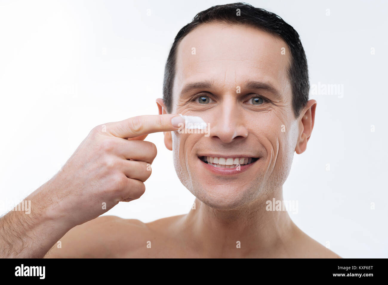 Portrait of a handsome happy man applying facial cream Stock Photo
