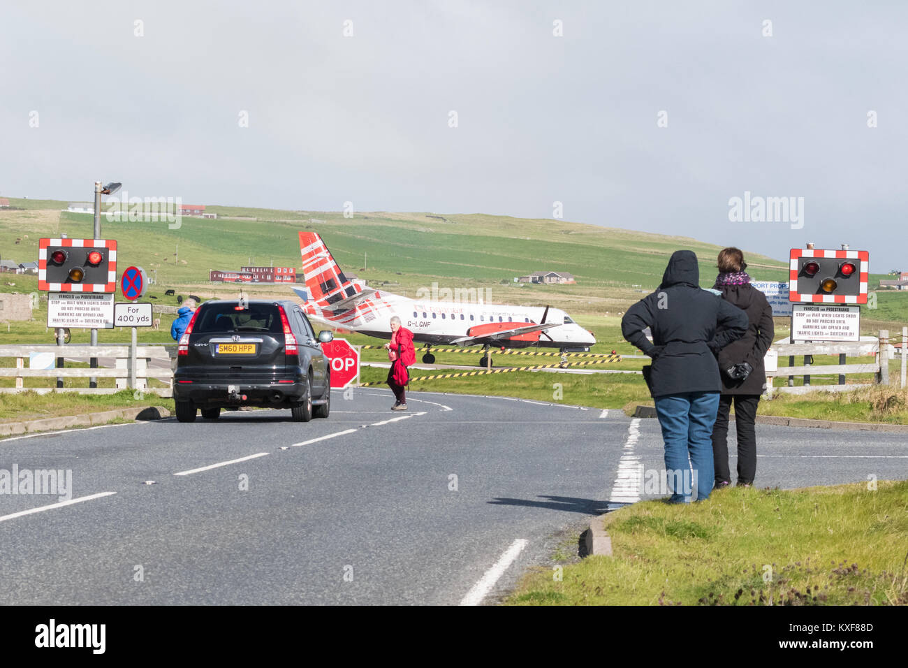 Sumburgh Airport, Shetland Islands, Scotland, UK - road crossing closed to allow Loganair flight to land, watched by tourists Stock Photo