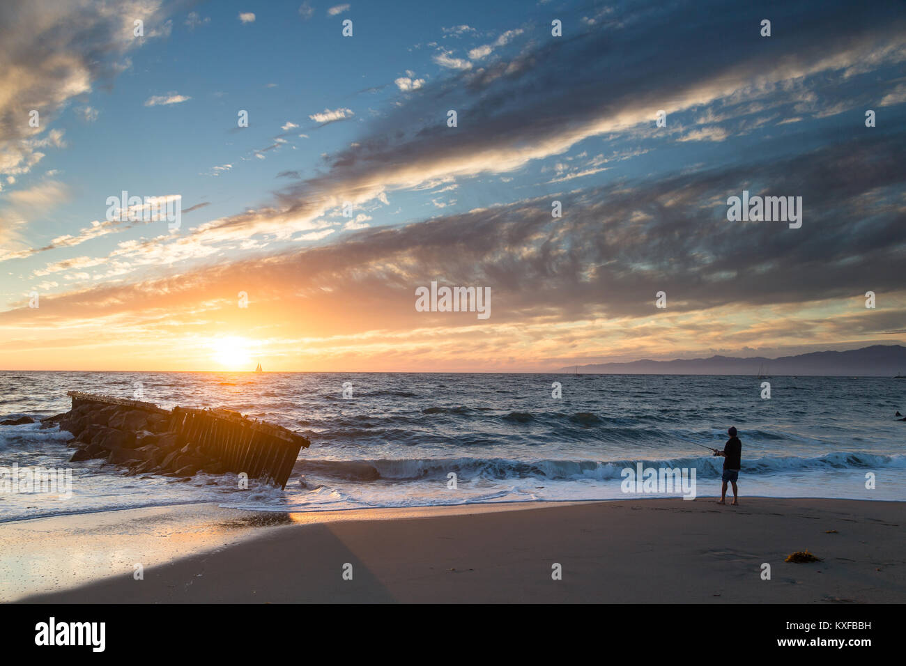 A fisherman fishes for perch from the beach at sunset in Playa Del Rey, California. Stock Photo