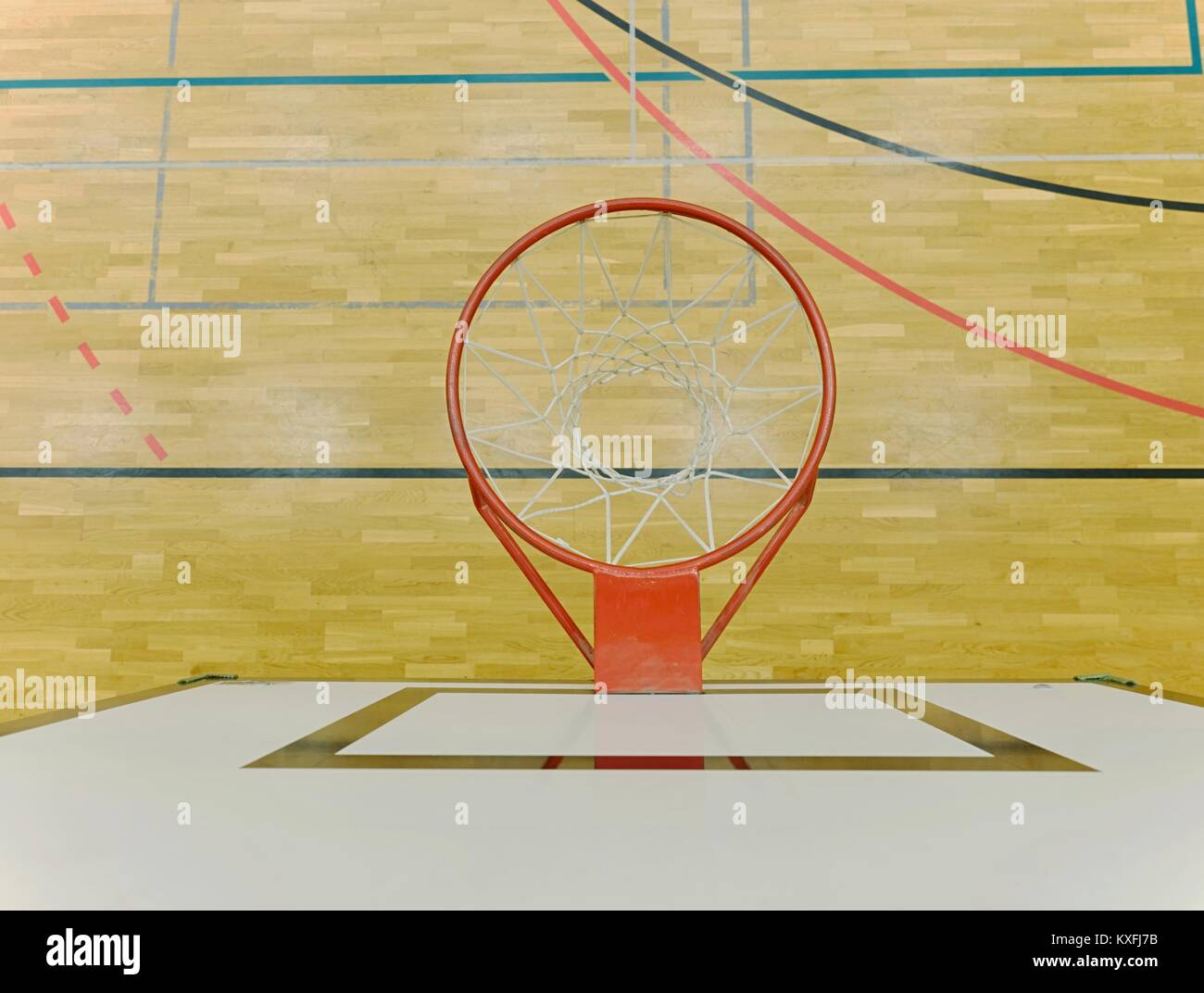 Interior of school gym with basketball board and basket. Safety nets