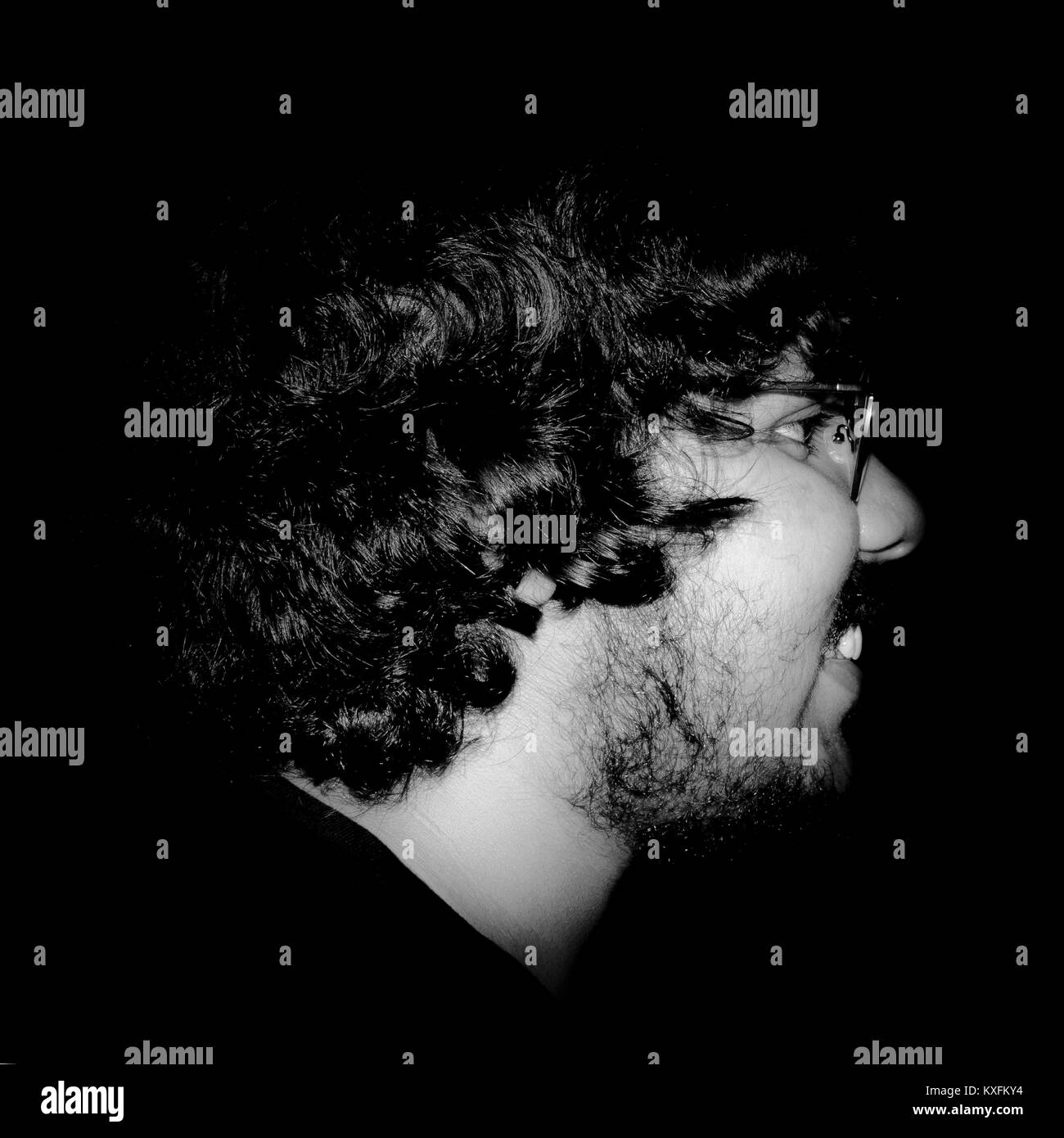 Side Profile Close-up Portrait Of Young Man With Eyeglasses Against Black Background. Stock Photo