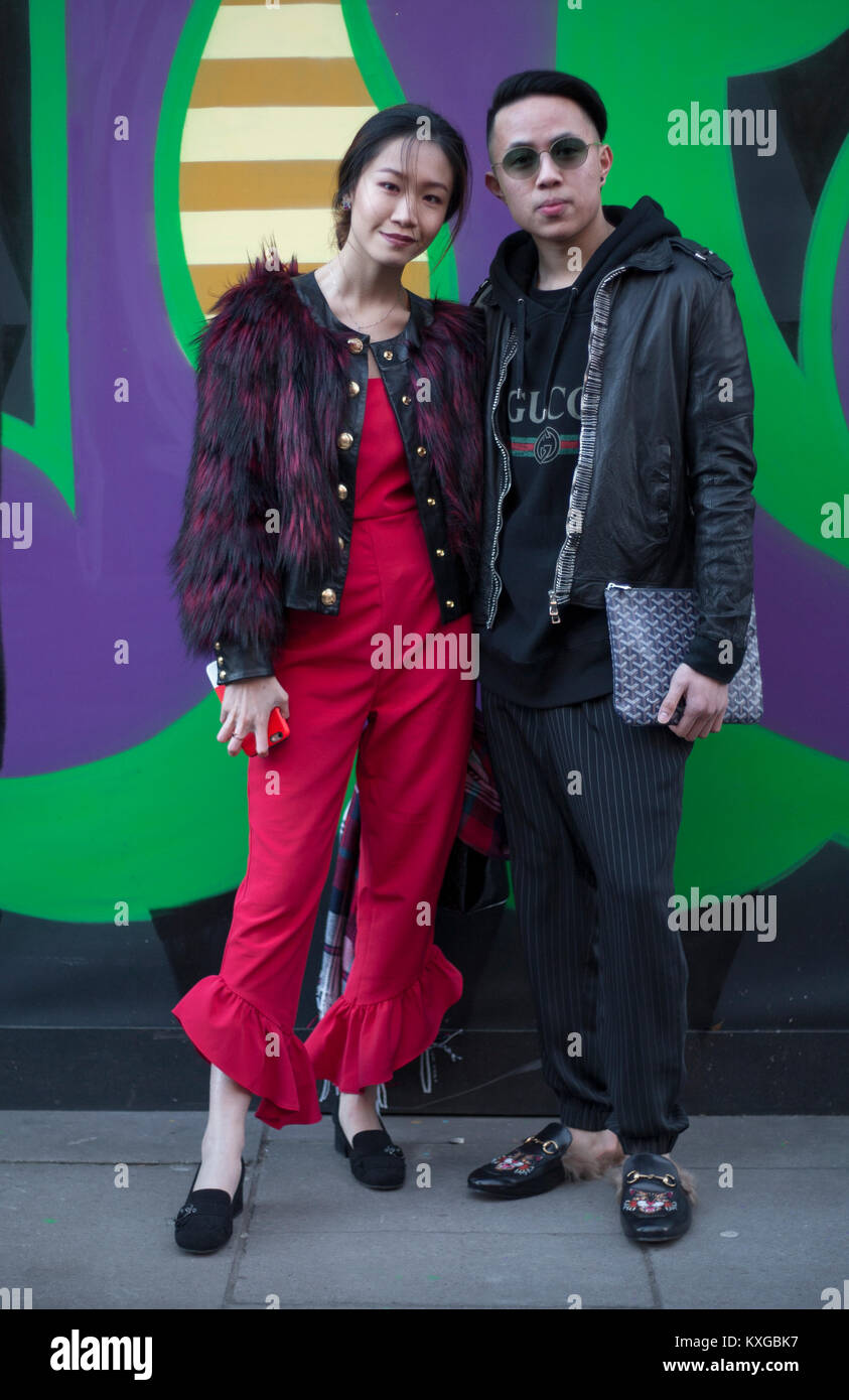 Street Style from day two of London Fashion Week Mens AW 2018. Image shows  a couple posing for a picture. Claire from Hong Kong wears a jacket by  Balmain, a red jumpsuit