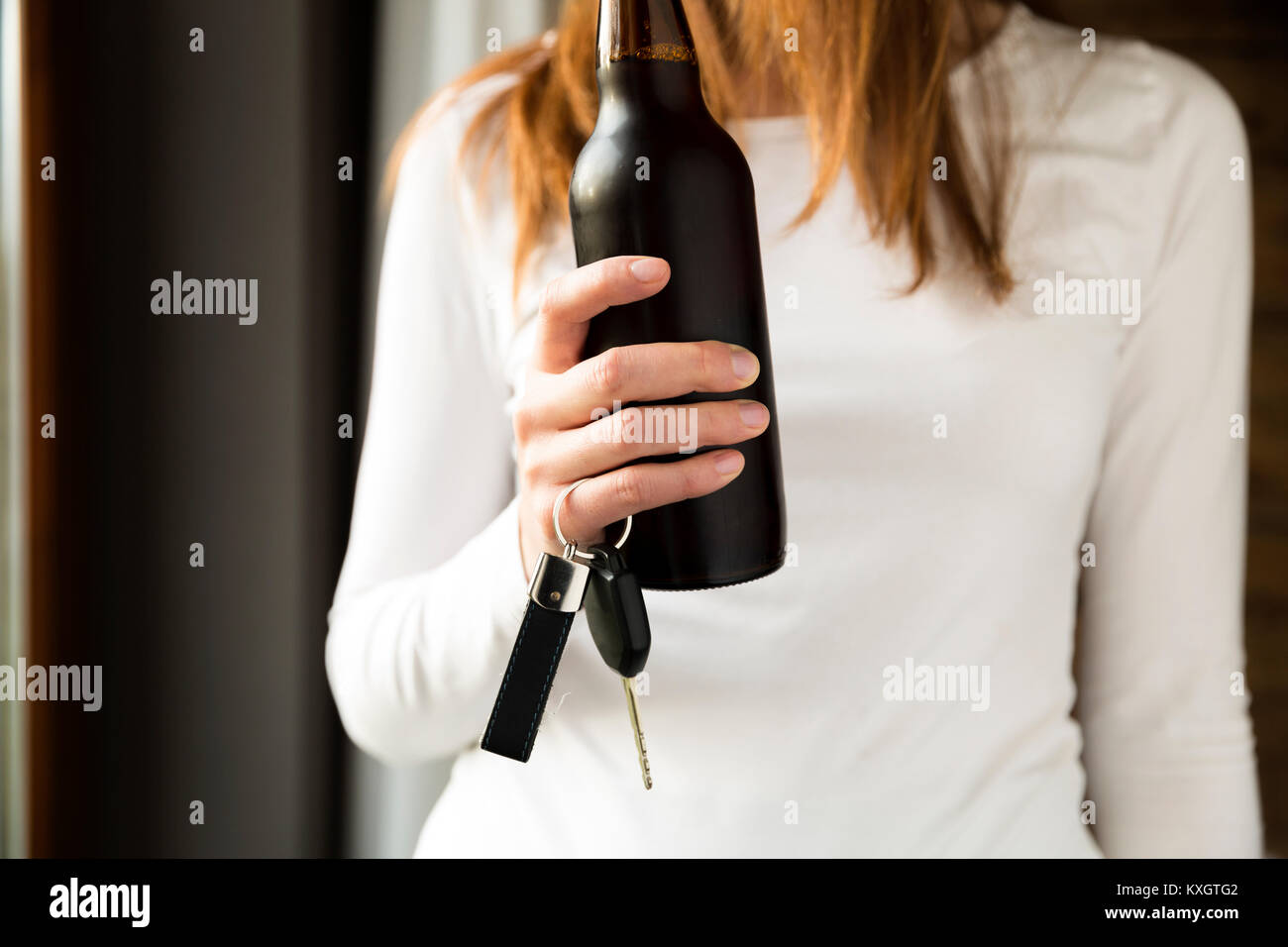 Do not drink and drive concept. Woman holding bottle of beer and car keys in hand Stock Photo
