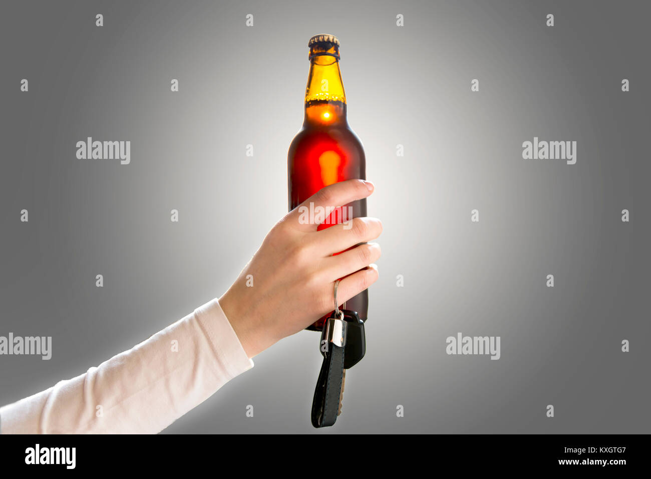 Woman's hand holding bottle of beer and car keys. Do not drink and drive concept Stock Photo