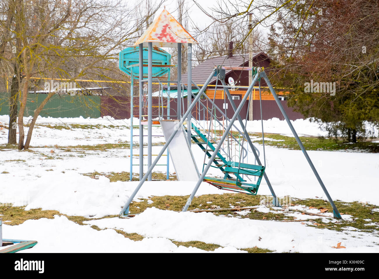 Children's playground in winter under snow. Swing, carousel and slide. Winter desolation Stock Photo