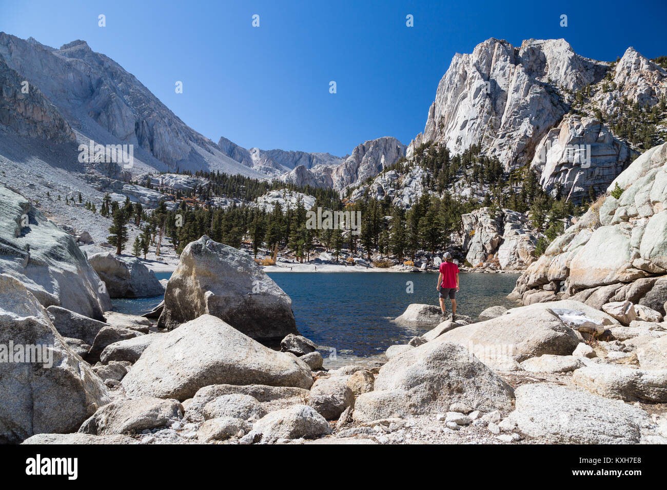 A man admires the view of Lone Pine Lake looking up towards the Sierra Nevada Mountains and the route to Mt. Whitney. Stock Photo