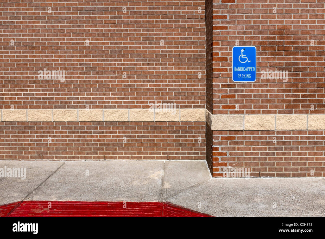 Blue handicapped parking sign on a red brick wall of an office building in the United Sates of America; Concept for parking for disable people Stock Photo