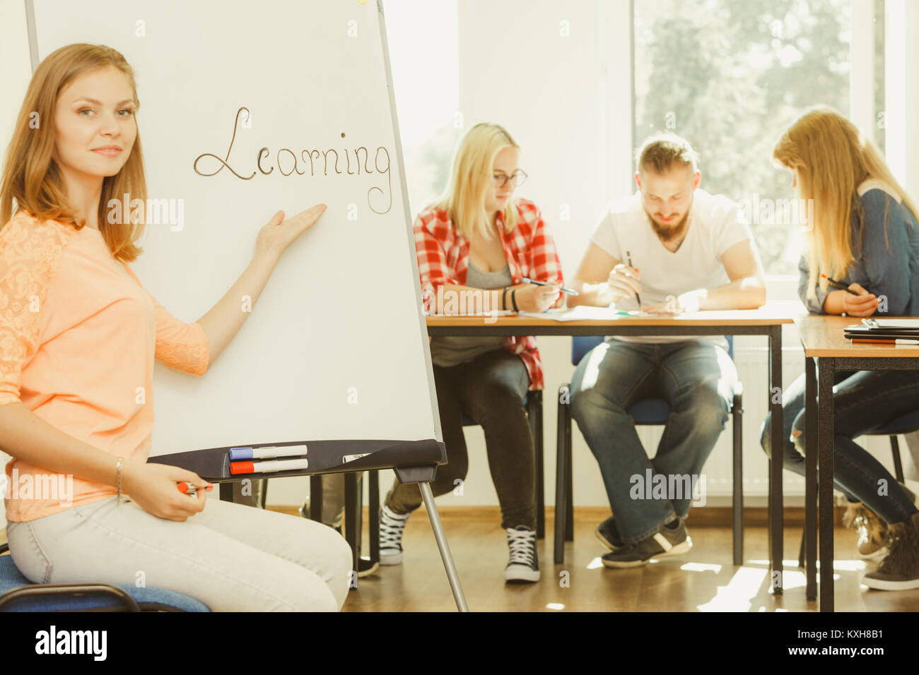 Education, knowledge, wisdom and learn new things concept - student girl writing Learning word on whiteboard in front of students her group mates in c Stock Photo