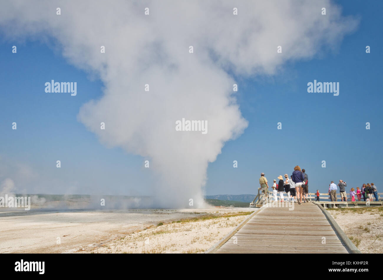 People visiting Yellowstone national park, wooden path an steam from a hot spring Stock Photo