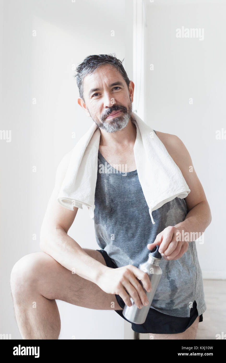 Midsection Of Man Holding Water Bottle While Standing Against Wall stock  photo