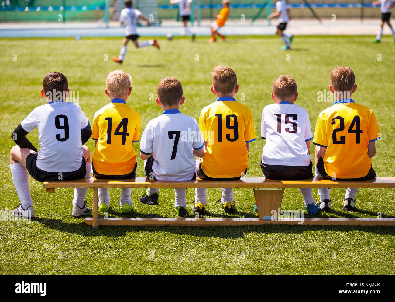 Young Football Players. Young Soccer Team Sitting on Wooden Bench. Soccer Match For Children. Young Boys Playing Tournament Soccer Match. Youth Soccer Stock Photo
