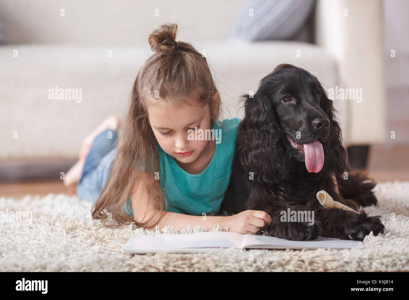 Cute girl reading book while lying by dog on rug at home Stock Photo