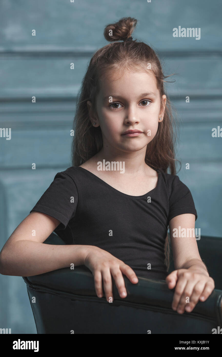 Portrait of cute girl sitting on armchair at home Stock Photo