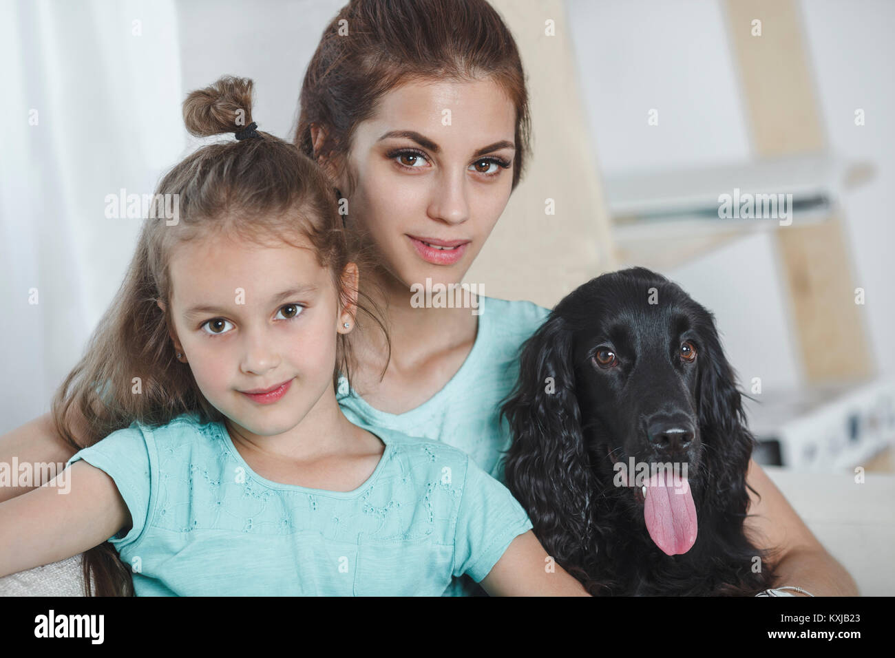 Portrait of beautiful young woman with daughter and dog at home Stock Photo