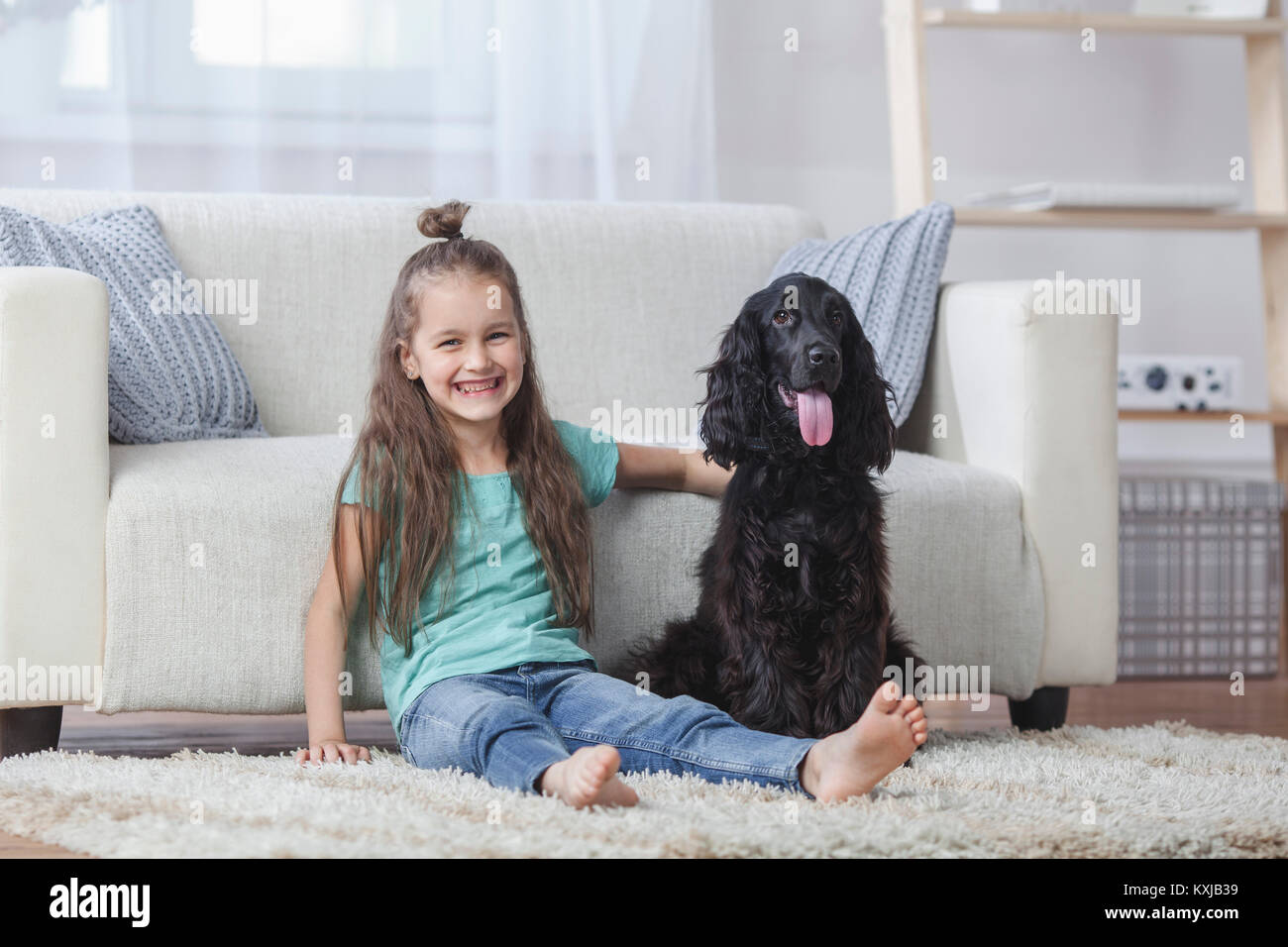 Portrait of cute girl sitting by Cocker Spaniel on rug at home Stock Photo