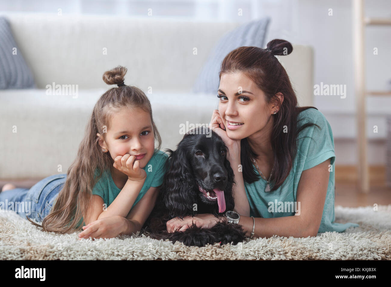 Portrait of mother and daughter lying with dog on rug at home Stock Photo