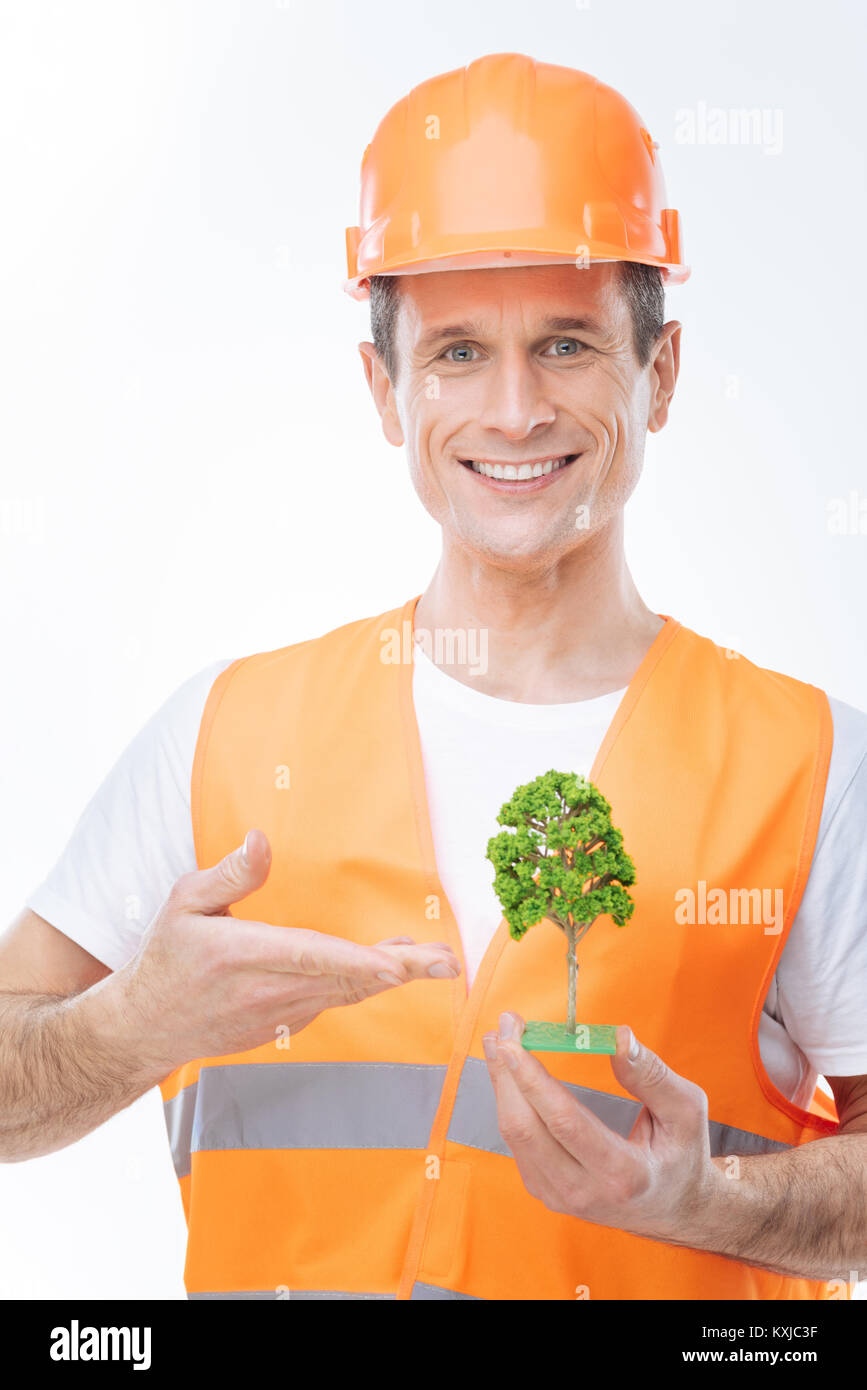 Delighted happy engineer pointing at the tree model Stock Photo - Alamy