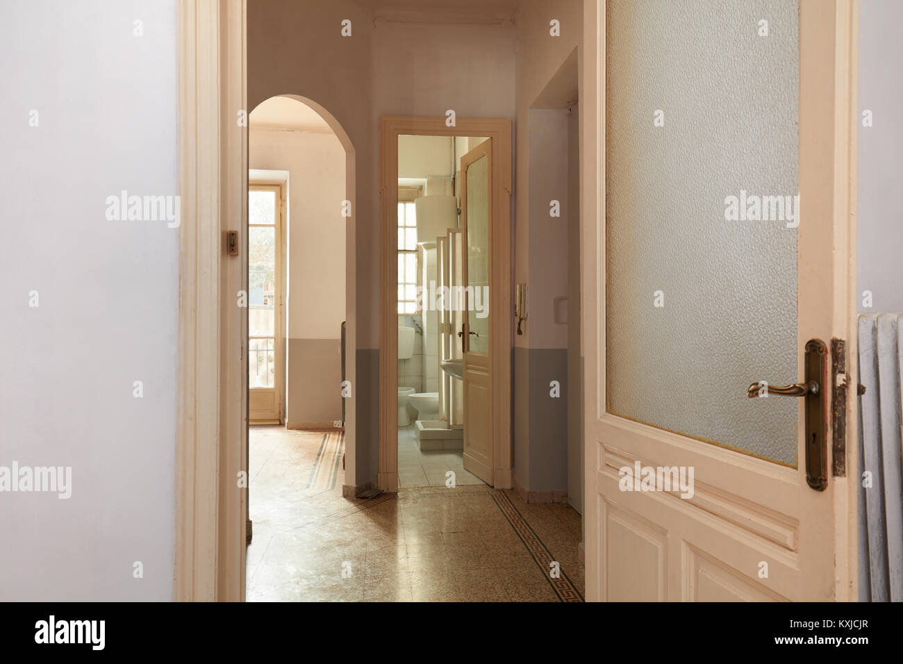 Old apartment interior view with open wooden door and tiled floor Stock Photo
