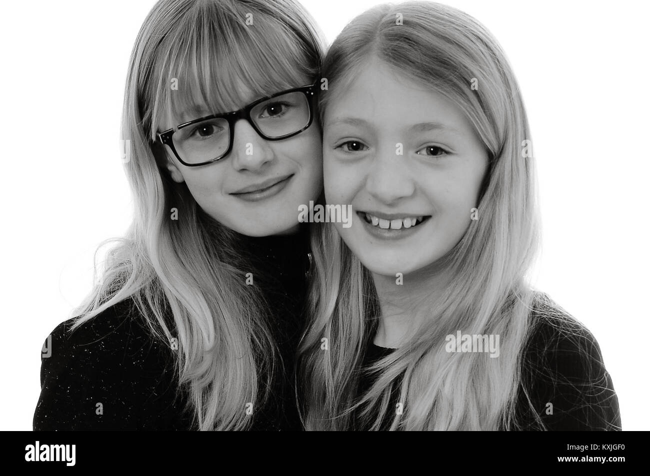 two pretty blonde Caucasian girls smiling and hugging, isolated on white, in monochrome Stock Photo