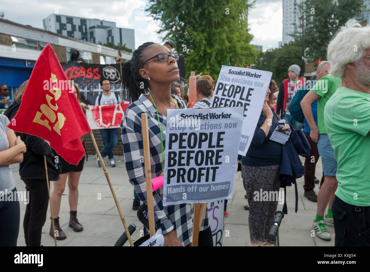 A woman holds a placard 'Stop evictions now People Before Profit Hands off our homes' as she