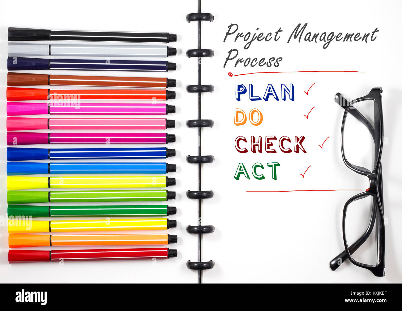 Project Management Process text on white sketchbook with color pen and eye glasses, Top View/Flat Lay Stock Photo