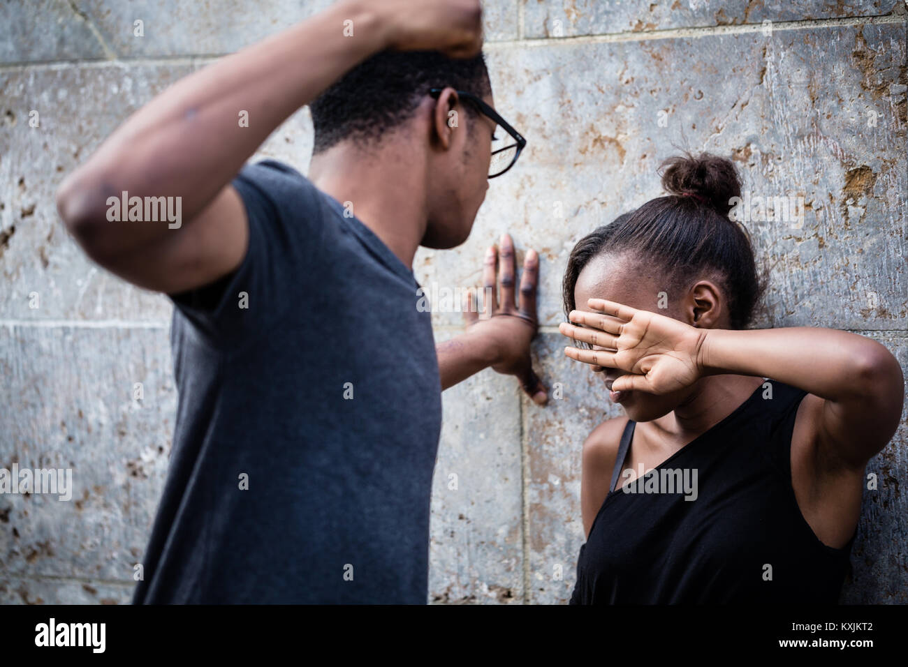 Violent young man threatening his girlfriend with his fist outdo Stock Photo