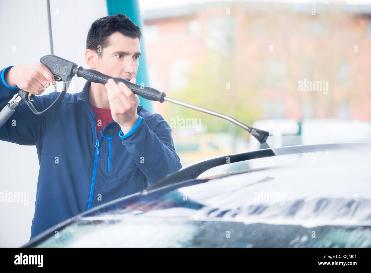 Dedicated worker washing car with highpressure hose Stock Photo Alamy