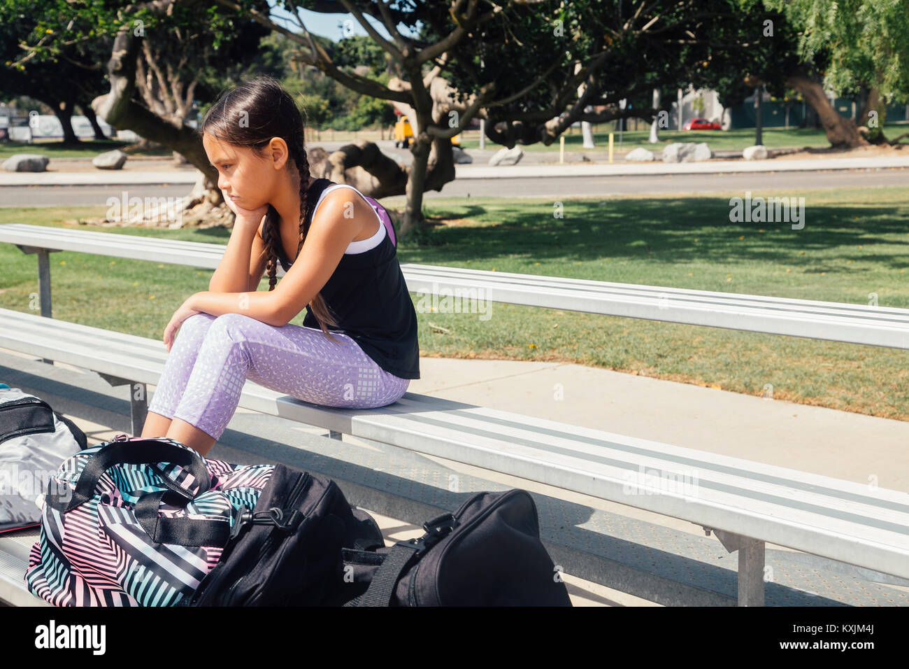 Schoolgirl soccer player alone on bench on school sports field Stock