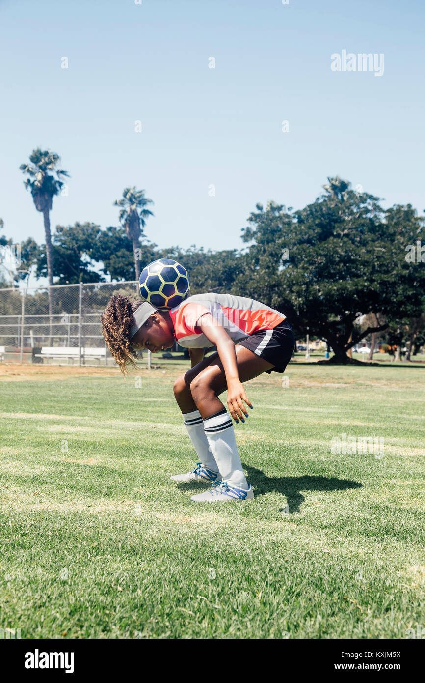 Teenage schoolgirl soccer player balancing ball on shoulders on school sports field Stock Photo