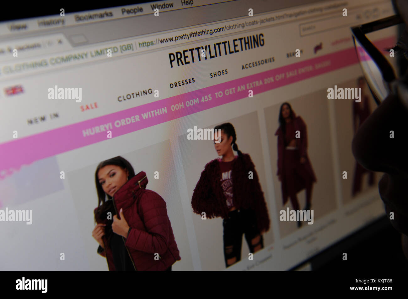 A woman browses on the PrettyLittleThing online fashion retailer Stock Photo