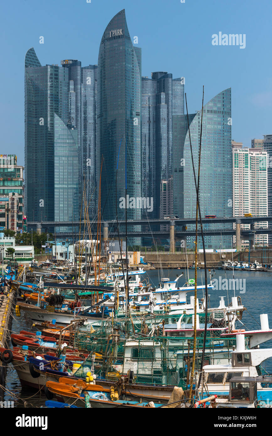 Rows of old fishing boats moored at Centum city, Busan, contrasting with the modern skyscrapers to the rear. South Korea. Stock Photo