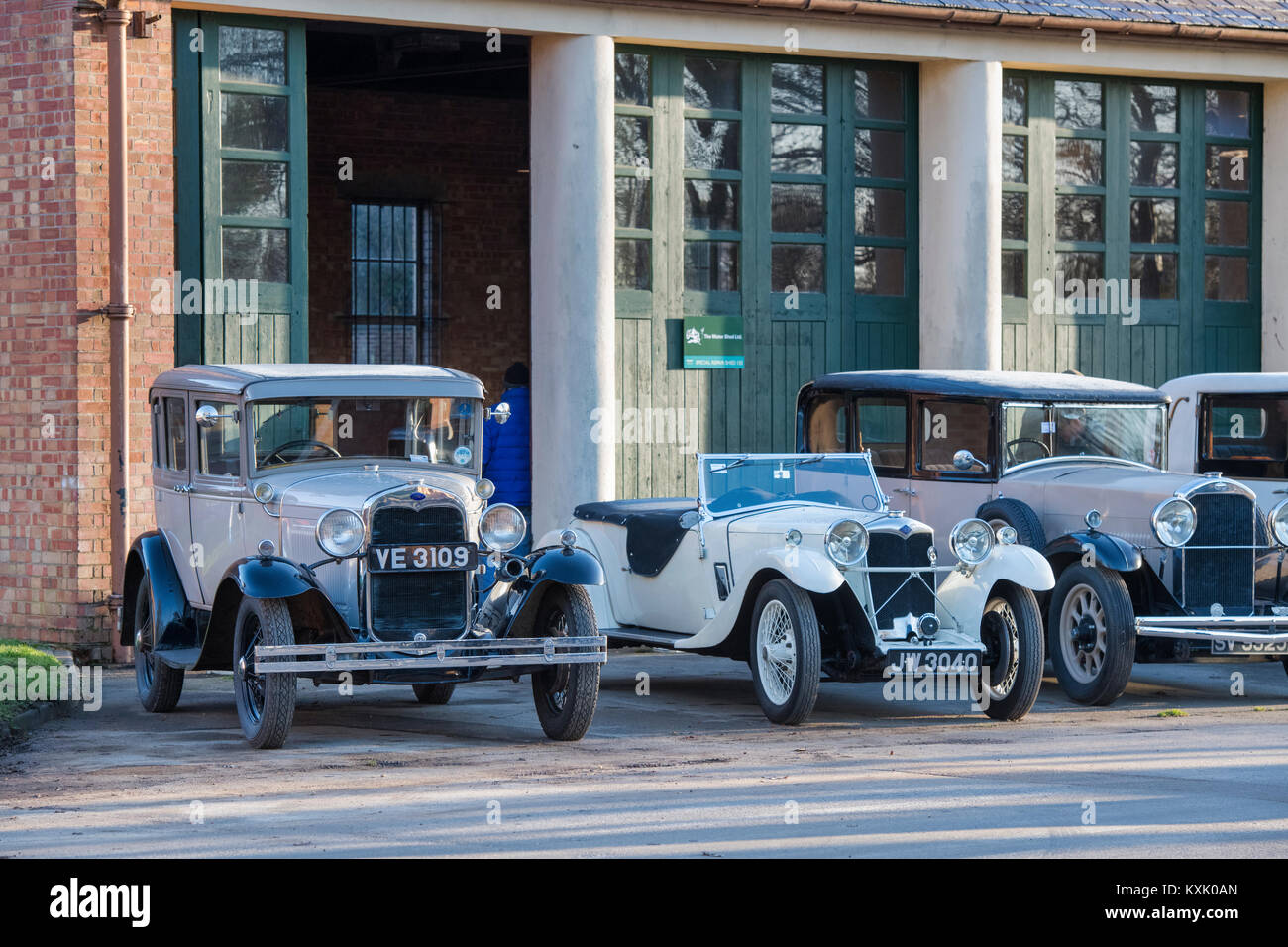 Line of Vintage cars outside a garage at Bicester Heritage centre. Bicester, Oxfordshire, England. Stock Photo